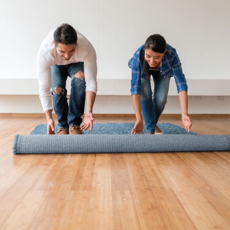 Couple rolling out area rug on new Hardwood floor